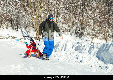 Heureux père et son fils bénéficiant de traîneau ride. Famille heureuse à traineau en hiver avoir du plaisir ensemble. Sortie rapide. Sous la conduite de la famille hiver traîneau Banque D'Images