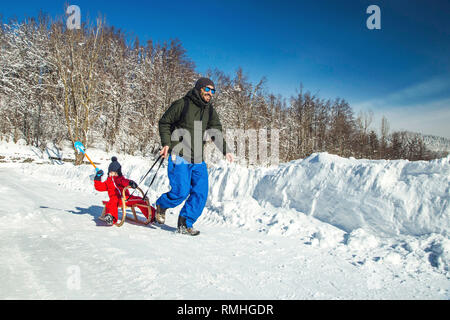 Heureux père et son fils bénéficiant de traîneau ride. Famille heureuse à traineau en hiver avoir du plaisir ensemble. Sortie rapide. Sous la conduite de la famille hiver traîneau Banque D'Images