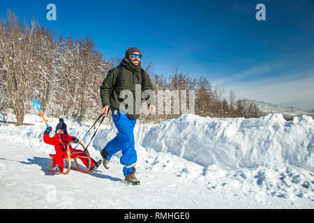 Heureux père et son fils bénéficiant de traîneau ride. Famille heureuse à traineau en hiver avoir du plaisir ensemble. Sortie rapide. Sous la conduite de la famille hiver traîneau Banque D'Images