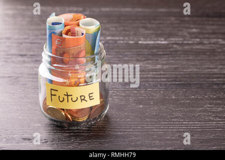 Bocal en verre avec des pièces et billets euro inscription future. Sur l'ancien tableau noir. Le concept de l'épargne pour le développement Banque D'Images