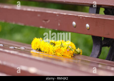 Bonjour, l'été. Une guirlande de pissenlits sur un banc en bois. Dans le parc en été. Date romantique, Déclaration d'amour. Banque D'Images