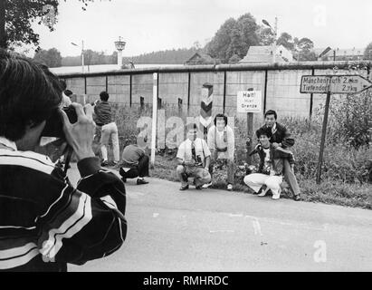 Un groupe de touristes japonais prend des photos à la frontière de la RDA en Bavière. Juste à côté d'un panneau d'avertissement de la Police Fédérale des Frontières, la marque d'un Muenchenreuth et Tiefendorf à Hof. Dans l'arrière-plan, une tour de guet. Banque D'Images