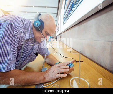 STRASBOURG, FRANCE - Sep 21, 2018 : side view of man curieux Apple test Beats by Dr Dre écouteurs Apple avec la musique sur le nouvel iPhone Xs Max dans les smartphones Apple Store moderne Banque D'Images