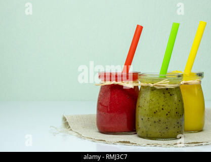 Fraise, kiwi et mangue smoothies en pots mignon avec tubes à cocktails. Banque D'Images