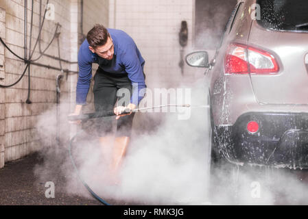 Lave-auto manuel avec de l'eau sous pression en lavage de voiture à l'extérieur . Banque D'Images