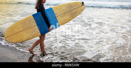 Young attractive et heureux surfer girl dans belle plage de surf jaune autour de l'océan profiter de vacances d'été à l'île tropicale