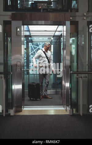 Businessman with travel suitcase dans l'ascenseur Banque D'Images