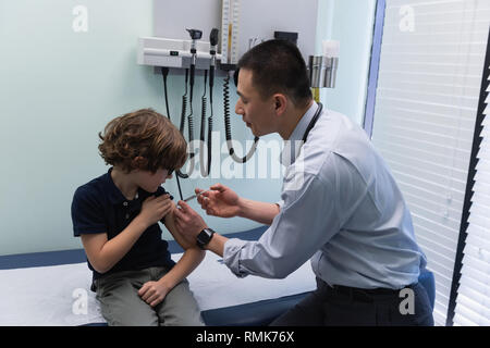 Young Asian male doctor injecting seringue à caucasian boy patient dans un centre Banque D'Images