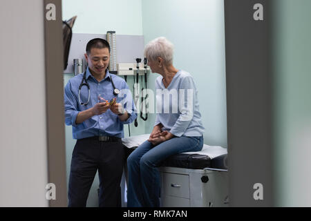 Les jeunes hommes asiatiques et médecin senior patient discuter sur modèle ear Banque D'Images