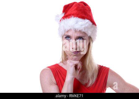 Femme en colère de défi dans une ambiance festive rouge Santa Hat pour célébrer la saison de Noël brillant à l'appareil photo avec un froncement de sourcil et son menton sur sa main isolé Banque D'Images