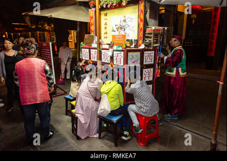 Les spectateurs chinois regarder un Peking peep show dans un parc à Shenzhen, Chine Banque D'Images