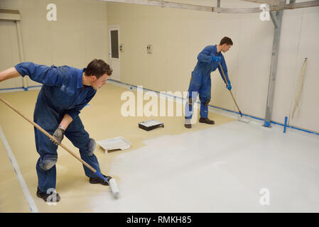 La dernière couche de roulement de métier d'epoxy produit sur le plancher d'un bâtiment industriel Banque D'Images
