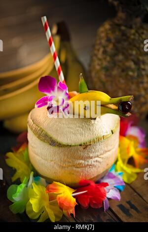 Tiki Funky cocktail servi dans un ananas frais avec une banane dolphin garnir Banque D'Images