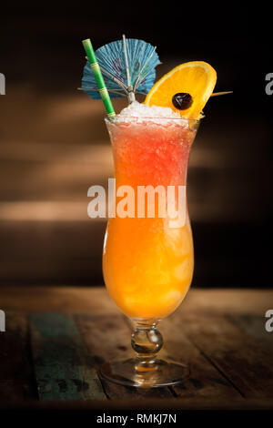 Tiki célébration cocktail servi dans un verre d'ouragan avec un parapluie, une cerise et une orange. Banque D'Images