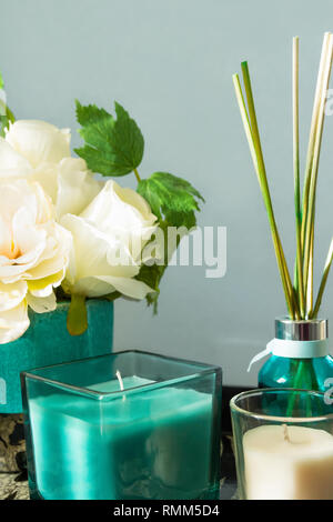 Diffuseur avec des bâtons en bouteille en verre turquoise bougies bouquet de fleurs sur fond de mur gris de table. L'Aromathérapie home décor intérieur Banque D'Images