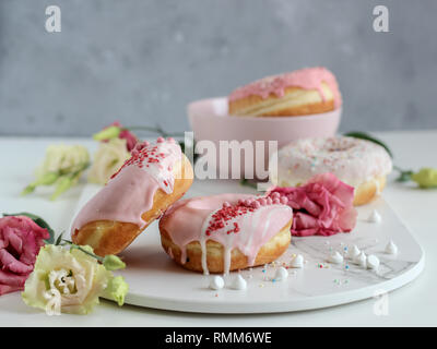 Une pile de donuts rose avec des fleurs sur fond sombre Banque D'Images
