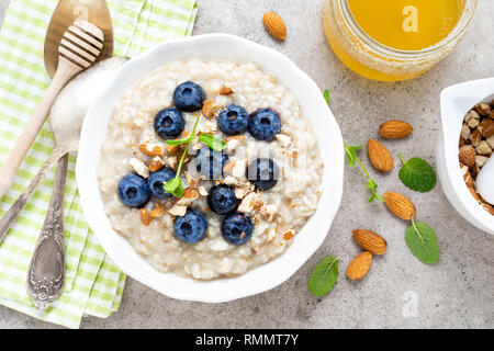 Avec l'avoine, de bleuets frais noix d'amande et de miel pour le petit déjeuner Banque D'Images
