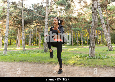 Image de femme énergique 20s vêtu de noir tracksuit le sport dans Green Park Banque D'Images