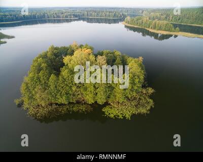 Vue aérienne de la petite île inhabitée (Wyspa Pozeracza SERC) sur le lac avec sky reflète dans l'eau calme pendant la saison d'Automne, lac Krzywa Kuta, Mazurie Banque D'Images