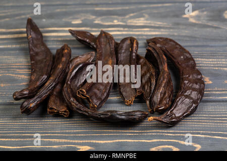 De caroubiers. Des gousses de caroube bio au gris sur fond de bois libre. Banque D'Images