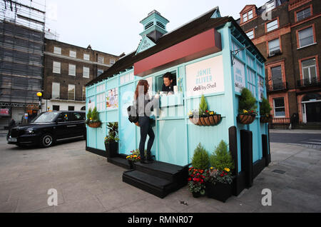 Jamie Oliver teste de nouvelles on-the-go gamme alimentaire à son plus petit eatery jusqu'à ce jour, une maison d'hébergement traditionnel cabmen à Russell Square, d'annoncer le lancement de Jamie Oliver deli par Shell, Londres. Chauffeurs et passants de la queue à un refuge pour cocher traditionnels à Russell Square, à test routier, la nouvelle gamme de Jamie Oliver deli par Shell. Le nouveau menu inclut des en-cas tels que fruits rouges Superfood Hot Pot, porridge, d'Œufs et Bacon Bean Pot chaud, méditerranéen & veggie rôti, un enveloppement à la ricotta fromage fumé et épicé salade sandwich au poulet chipotle de même qu'une nouvelle boîte de repas des enfants qui proposera un ry Banque D'Images