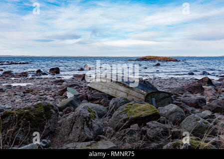 Old Grey bateau à rames à l'envers sur une plage rocheuse en Suède januari 2019 Banque D'Images