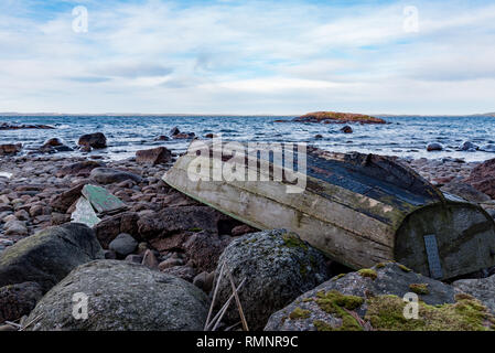 Old Grey bateau à rames à l'envers sur une plage rocheuse en Suède januari 2019 Banque D'Images