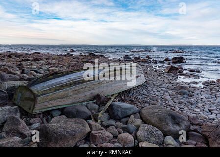 Old Grey bateau à rames à l'envers sur une plage rocheuse en Suède januari 2019 Banque D'Images