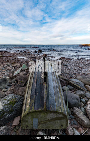 Old Grey bateau à rames à l'envers sur une plage rocheuse en Suède januari 2019 Banque D'Images