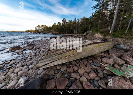 Old Grey bateau à rames à l'envers sur une plage rocheuse en Suède januari 2019 Banque D'Images