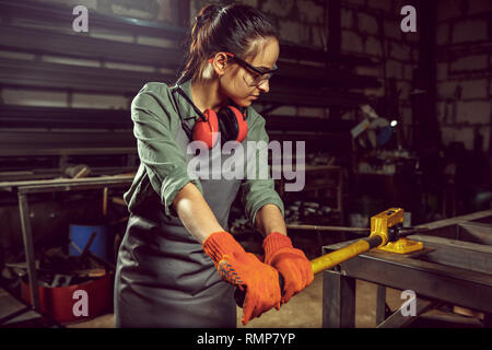 Occupé et artisane grave bois broyage avec machine spéciale. Belle femme portant des lunettes de sécurité. Concept de l'atelier du menuisier et le travail du bois. L'égalité des sexes. Profession masculine Banque D'Images