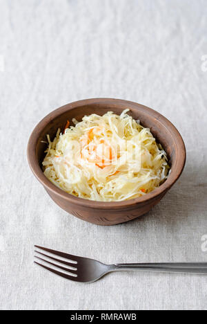 À partir de au-dessus du bol d'argile a été pleine de choucroute sur tableau blanc juteux avec la fourchette Banque D'Images