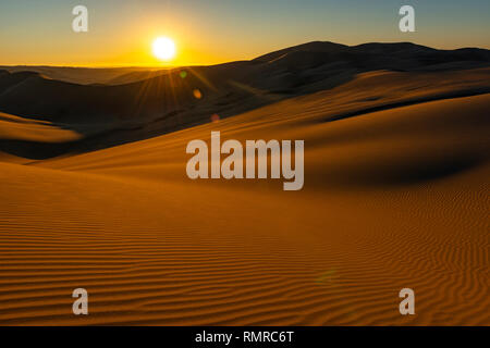 Coucher du soleil avec des reflets et sable ondulations dans l'avant-plan dans le désert de la côte du Pérou situé entre l'Ica, Nazca Huacachina et, au sud de Lima, Pérou. Banque D'Images