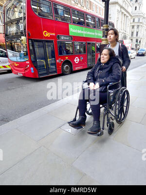 Londres, Angleterre, Royaume-Uni. Femme être poussé dans un fauteuil roulant dans Whitehall comme un laissez-passer d'autobus Banque D'Images