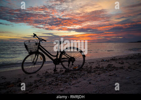 Silhouette de vintage vélo avec un panier sur la plage dans la soirée sur fond coucher de soleil Banque D'Images