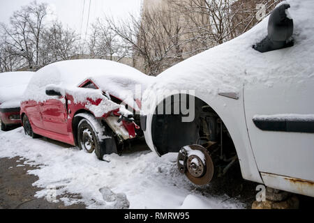 Deux voitures endommagées, un rouge et un blanc, recouvert de neige, assis en face de l'autre dans une ligne de voitures cassées, en attente de réparation à l'intérieur d'une fonction se Banque D'Images