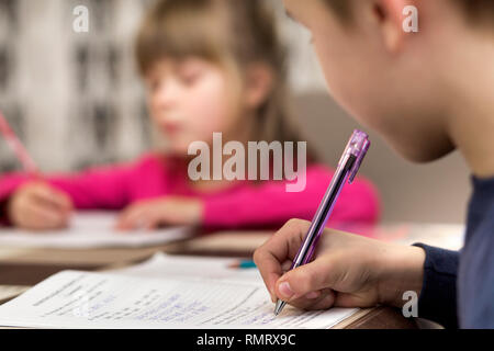 Deux jolies jeunes enfants, garçon et fille, frère et soeur à faire des devoirs, sur l'écriture et le dessin à la maison sur l'arrière-plan flou. L'éducation artistique, de la créativité Banque D'Images