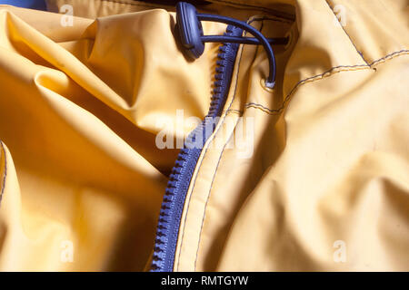 Imperméable jaune avec fermeture Éclair en plastique bleu Banque D'Images
