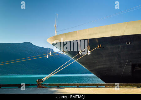 Bow, garde-rats et d'amarrage de bateau de croisière amarré dans le terminal en eau profonde de l'Alaska, dans l'après-midi clair soleil, avec aqua ocean et montagnes en Banque D'Images