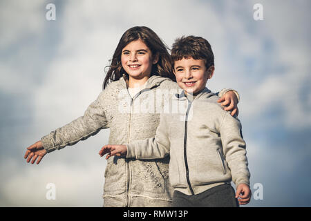 Portrait de deux enfants heureux sur fond de ciel, petit frère et sœur s'amuser ensemble en plein air au printemps Banque D'Images