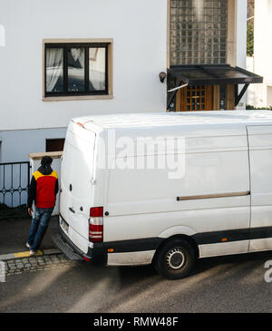 Paris, France - Nov 6, 2018 : augmentation de la vue de l'homme en uniforme de DHL à pied à l'arrêt white van après la prestation d'un nouveau colis Banque D'Images