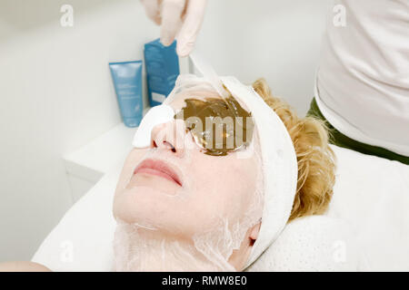 Travailleur coiffeur esthétique de l'application de masque du visage mer ​​Algae pour la lutte contre le vieillissement et l'hydratation de la peau à la cliente en instituts de beauté Banque D'Images