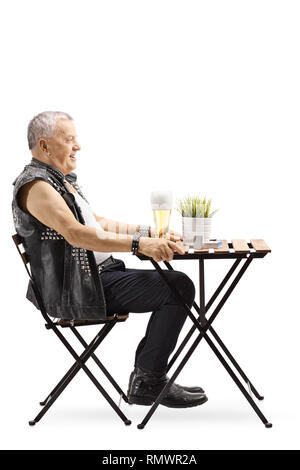 De toute la longueur un vieux punk homme assis à une table et boire de la bière isolé sur fond blanc Banque D'Images