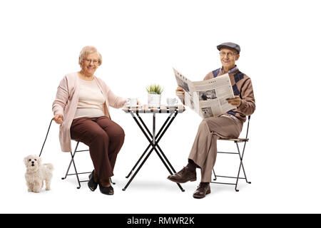 Couple assis à une table avec leur chien et savourer une tasse de café isolé sur fond blanc Banque D'Images