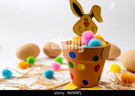 Les oeufs de pâques de diverses couleurs allongé sur la table à côté du vert et le lapin Banque D'Images