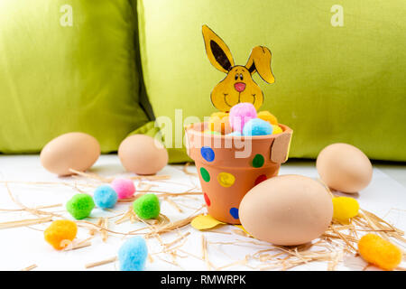 Les oeufs de pâques de diverses couleurs allongé sur la table à côté du vert et le lapin Banque D'Images