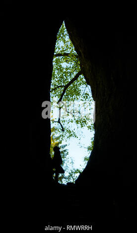 Une personne se penche à la sortie d'une grotte. contraste fort. Banque D'Images