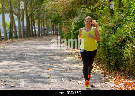 Femme d'âge moyen déterminé pendant le jogging entraînement cardio pour brûler des calories à l'extérieur dans le parc en automne Banque D'Images