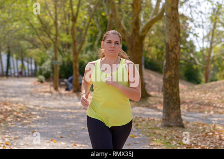 Femme d'âge moyen déterminé pendant le jogging entraînement cardio pour brûler des calories à l'extérieur dans le parc en automne Banque D'Images