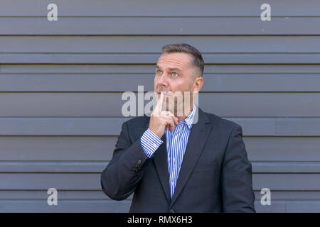 Portrait of mature thoughtful man wearing jacket debout sur un fond sombre Banque D'Images